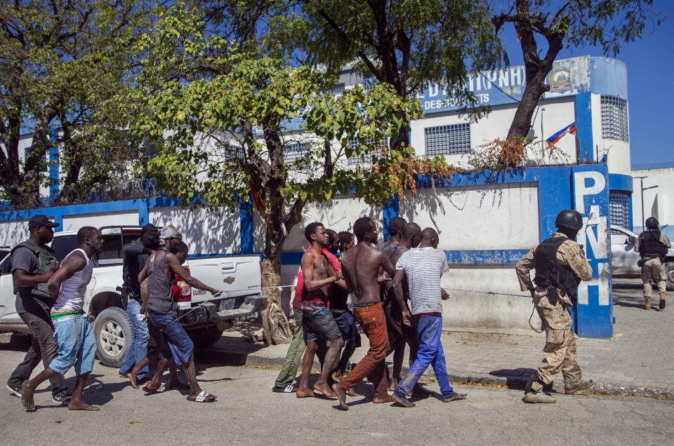 Recaptured inmates are escorted by police back to the Croix-des-Bouquets Civil Prison after an attempted breakout, in Port-au-Prince, Haiti, Thursday, Feb. 25, 2021. At least seven people were killed and one injured on Thursday after eyewitnesses told The Associated Press that several inmates tried to escape from a prison in Haiti’s capital. (AP Photo/Dieu Nalio Chery).