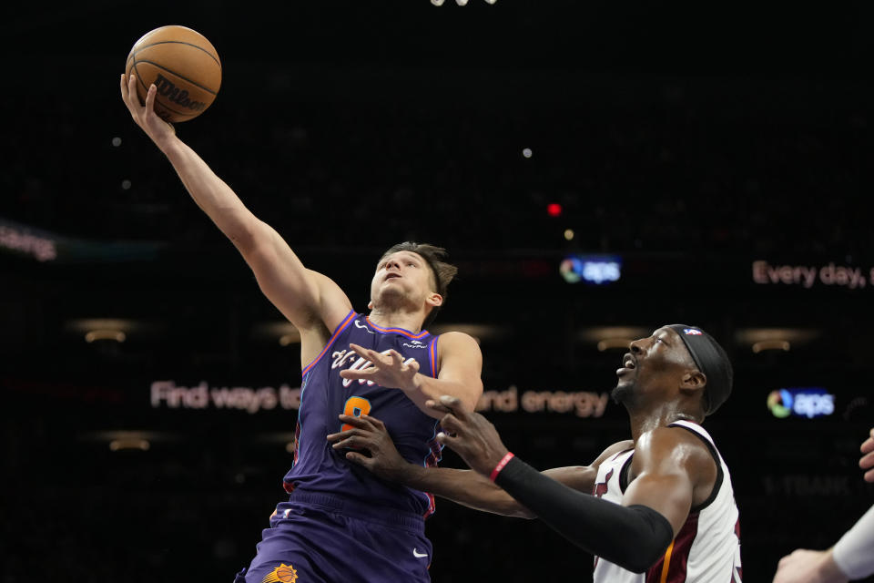 Phoenix Suns guard Grayson Allen, left, looks to shoot over Miami Heat center Bam Adebayo, right, during the first half of an NBA basketball game, Friday, Jan. 5, 2024, in Phoenix. (AP Photo/Rick Scuteri)