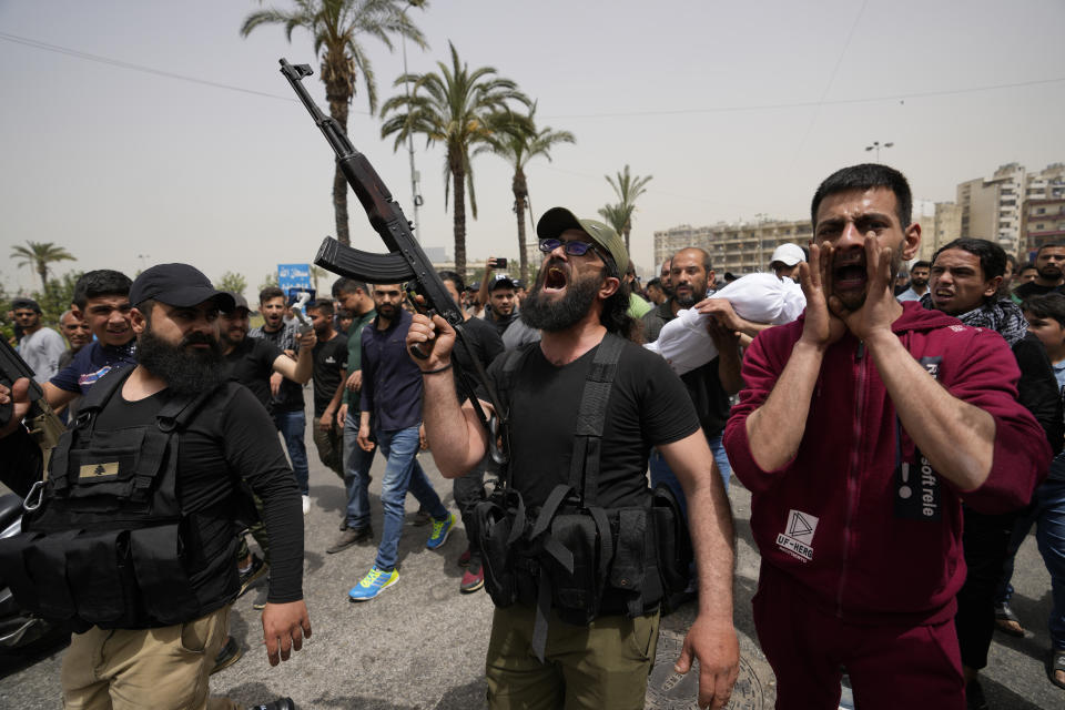 Gunmen fire in the air and shout slogans during the funeral procession for seven people killed when a boat packed with migrants sunk over the weekend as the Lebanese navy tried to force it back to shore, in Tripoli, north Lebanon, Monday, April 25, 2022. The small vessel was carrying nearly 60 people, many times its capacity, when the disaster struck on Saturday night. The tragedy was the latest in a growing trend involving mostly Lebanese and Syrians trying to travel to Europe from Lebanon in search of better lives. (AP Photo/Hassan Ammar)