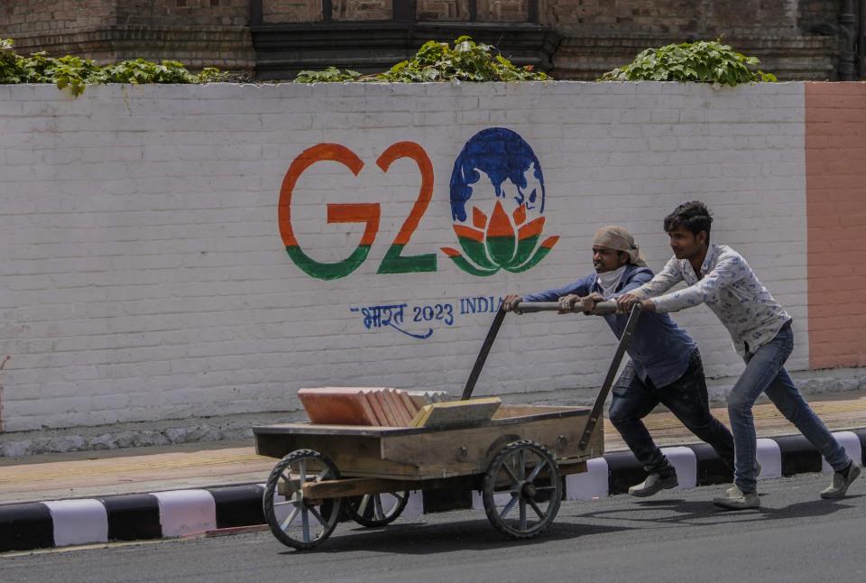 Workers push a handcart as they work on a newly renovated road ahead of G20 tourism working group meeting in Srinagar, Indian controlled Kashmir, Tuesday, May 16, 2023. Indian authorities have stepped up security and deployed elite commandos to prevent rebel attacks during the meeting of officials from the Group of 20 industrialized and developing nations in the disputed region next week. (AP Photo/Mukhtar Khan)