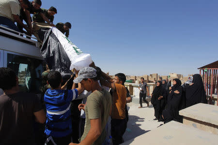 Mourners carry the coffin of Salah al-Wa'ili, a fighter from the Iraqi Shi'ite group Asa'ib Ahl al-Haq, during his funeral in Najaf July 12, 2014. REUTERS/Alaa Al-Marjani