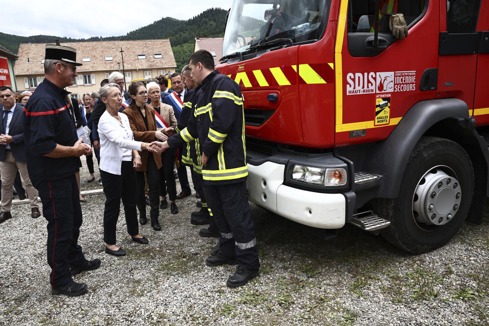 French Prime Minister Elisabeth Borne, 2nd left, shakes hands with a firefighter taking part in the rescue operations after a fire erupted at a holiday home for disabled people in Wintzenheim, France, Wednesday, Aug. 9, 2023. Eleven people have died after a fire ripped through a vacation home for adults with disabilities in eastern France. The deputy prosecutor of Colmar said 11 people who were sleeping on the upper floor and in a mezzanine area of the private accommodation were trapped by the fire, while five managed to escape. (Sebastien Bozon, Pool Photo via AP)