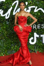 <p>in a strapless red gown with embellishments at the waist. </p>