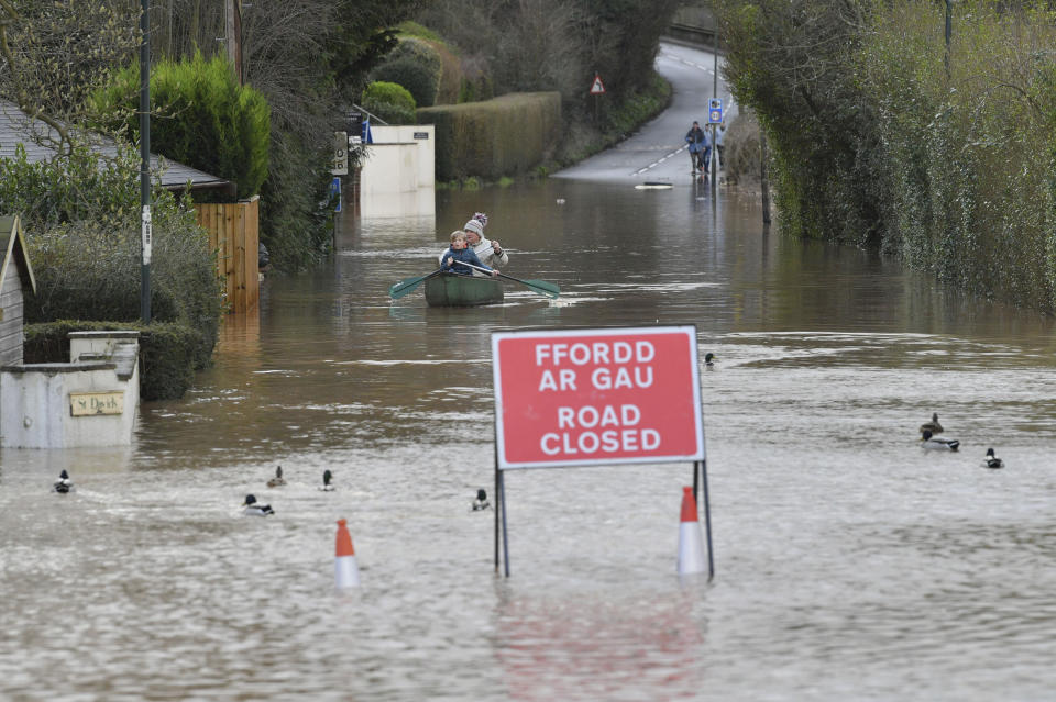 Nearby residents make their way through floodwater by boat in Monmouth, Wales, Tuesday Feb. 18, 2020. Britain's Environment Agency issued severe flood warnings Monday, advising of life-threatening danger after Storm Dennis dumped weeks' worth of rain in some places. (Ben Birchall/PA via AP)