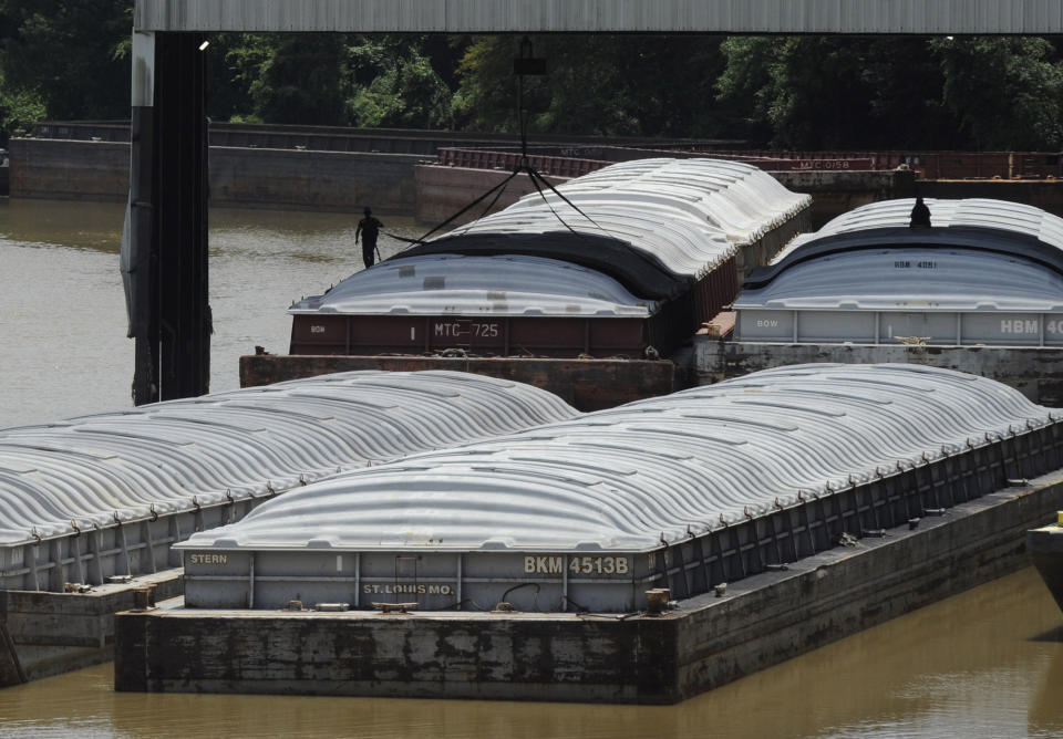 In this Monday, July 22, 2019 photo, men atop huge barges work along the Tennessee-Tombigbee Waterway in Columbus, Miss. While the waterway hasn't lived up to expectations in terms of traffic or economic development in parts of Alabama and Mississippi, cities including Columbus rely on it for jobs and transportation. (AP Photo/Jay Reeves)