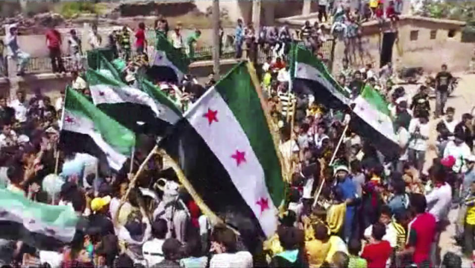 FILE - In this image made from amateur video released by the Shaam News Network and accessed, protesters carry Syrian revolutionary flags during a demonstration in Daraa, Syria, May 2, 2012. Protests spread Monday, Aug. 21, 2023, to new areas in southern Syria amid widespread anger over increasing prices, the crash of the Syrian pound and dwindling purchase power of most people in the war-torn country, opposition activists said. (Shaam News Network via AP, File)