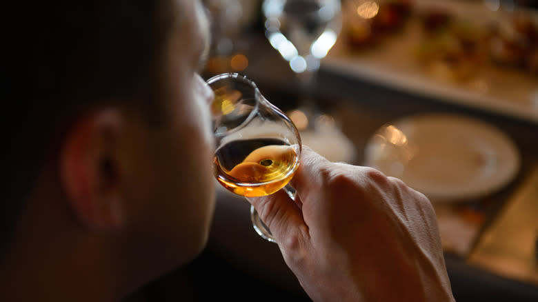 Person smelling whisky in a glass