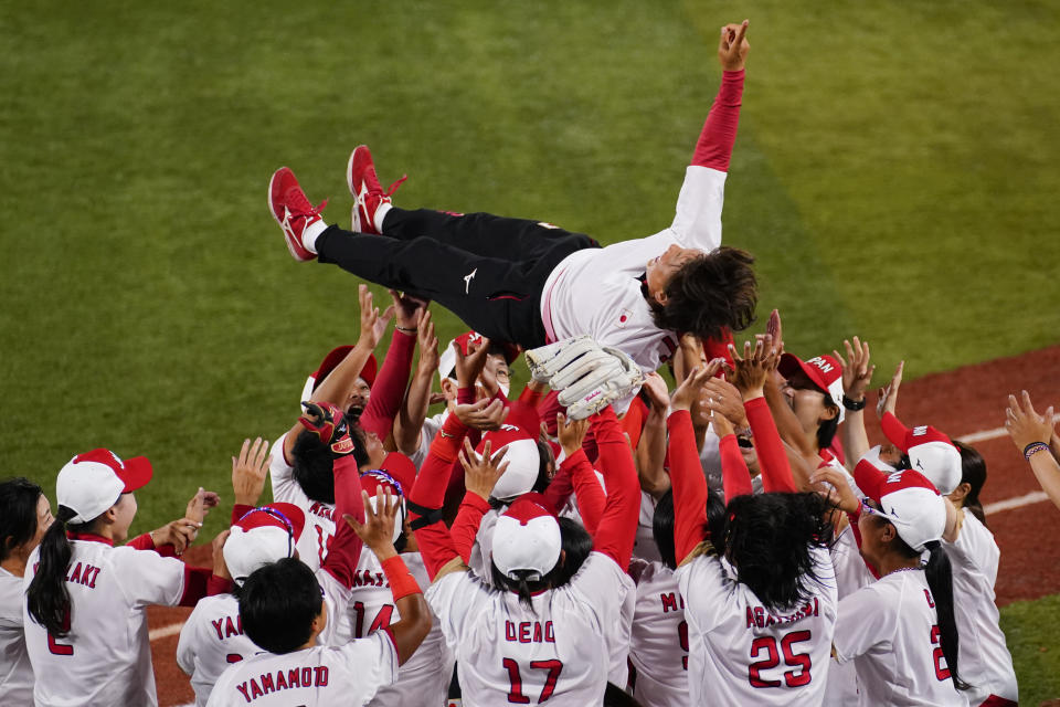 Members of team Japan celebrates with head coach Reika Utsugi after a a softball game against the United States at the 2020 Summer Olympics, Tuesday, July 27, 2021, in Yokohama, Japan. Japan won 2-0. (AP Photo/Matt Slocum)