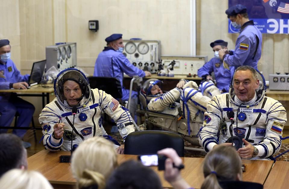 Members of the International Space Station (ISS) crew, U.S. astronaut Steven Swanson (L) and Russian cosmonaut Alexander Skvortsov (R) speak with relatives as Russian cosmonaut Oleg Artemyev (C) tests a space suit during pre-launch preparations at the Baikonur cosmodrome March 25, 2014. REUTERS/Maxim Shipenkov/Pool (KAZAKHSTAN - Tags: SCIENCE TECHNOLOGY TRANSPORT)