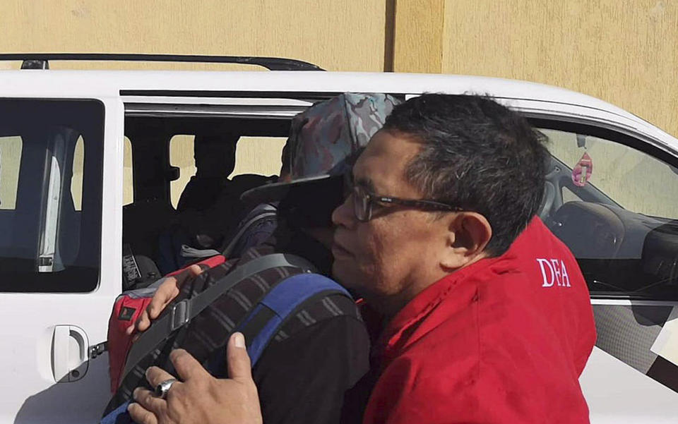 In this Wednesday, April 17, 2019, photo released by the Department of Foreign Affairs, a Filipino worker embraces a staff of the department as they are evacuated from Tripoli, Libya. Philippine diplomats started evacuating a small group of Filipinos from the Libyan capital after it was hit by a barrage of rocket fire that wounded one Filipino, officials said Thursday, April 18, 2019. (Department of Foreign Affairs via AP)