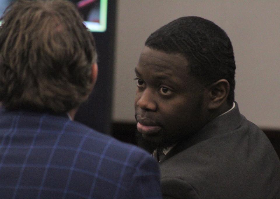 Othal Wallace speaks to one of his defense attorneys on Tuesday during his first-degree murder trial in the killing of Daytona Beach police officer Jason Raynor.