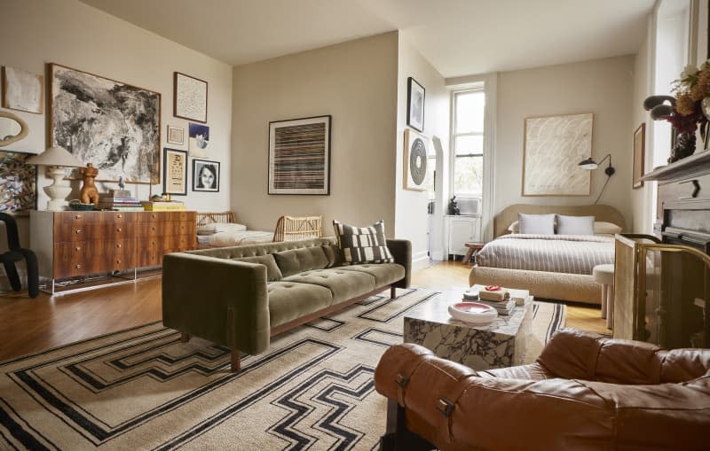 Green couch and leather lounge chair in the living area of a studio apartment.