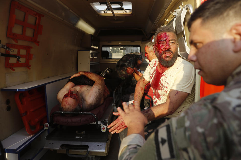 Un soldado libanés (derecha) revisa a un hombre herido que está sentado dentro de una ambulancia luego de una explosión en Beirut, Líbano, el martes 4 de agosto de 2020. (AP Foto/Hussein Malla)