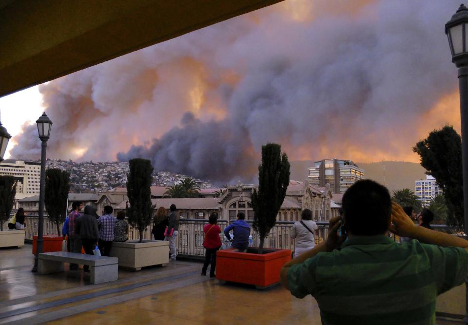 People look at smoke from a forest fire in Valparaiso city, northwest of Santiago April 12, 2014. More than 50 homes were burnt due to the forest fire but there have been no reports of injuries, local authorities said. REUTERS/Cesar Pincheira (CHILE - Tags: ENVIRONMENT DISASTER)