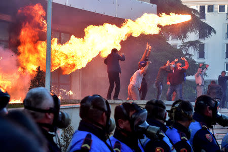 Flames are pictured behind a police formation during an anti-government protest in front of Prime Minister Edi Rama's office in Tirana, Albania May 11, 2019. REUTERS/Stringer