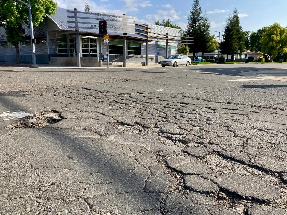 The roadway at the busy intersection of Placer and Continental streets near downtown Redding contains potholes and cracked pavement in front of the Shasta Community Health Center on Thursday, April 28, 2022.