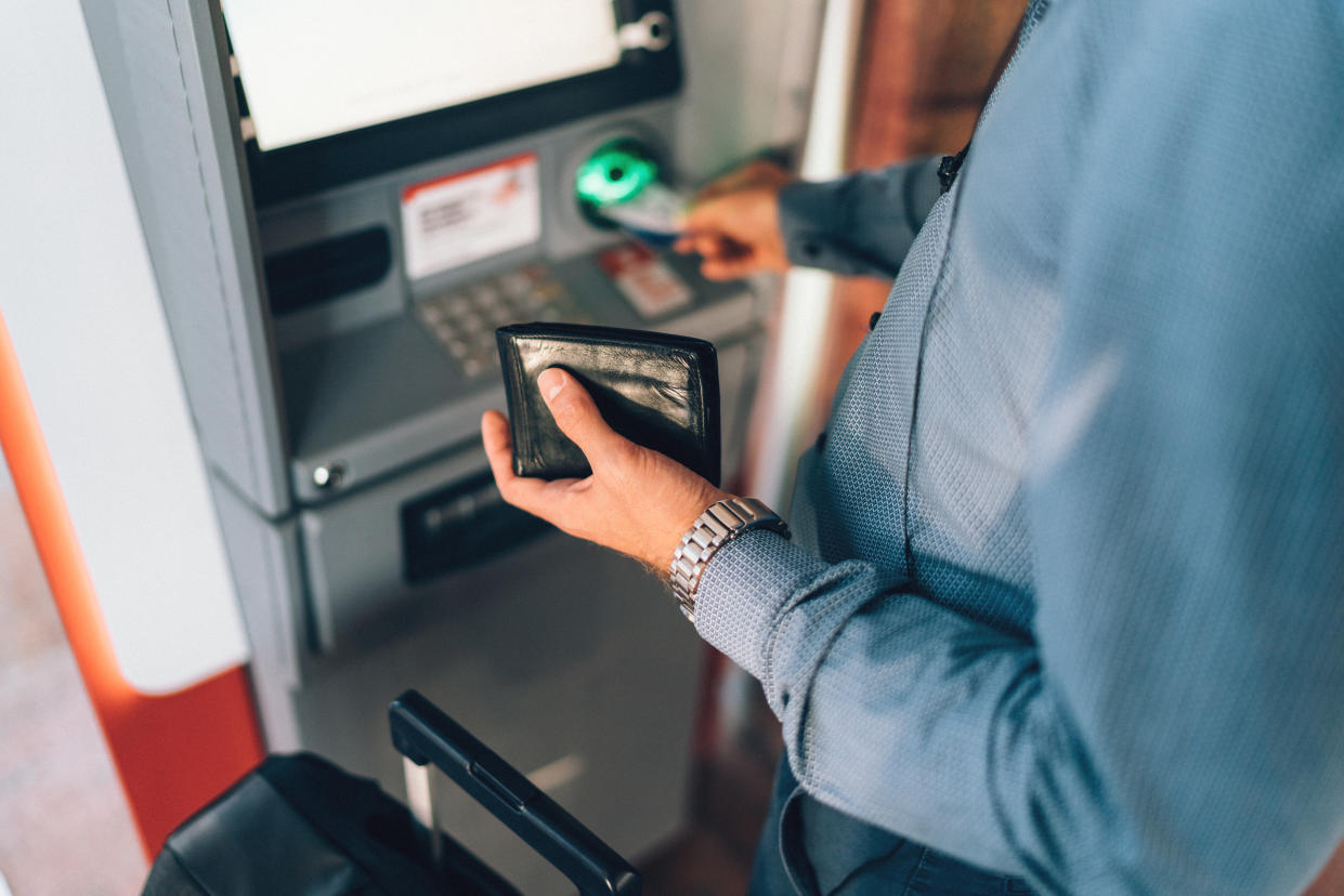 Businessman withdrawing money from ATM on airport