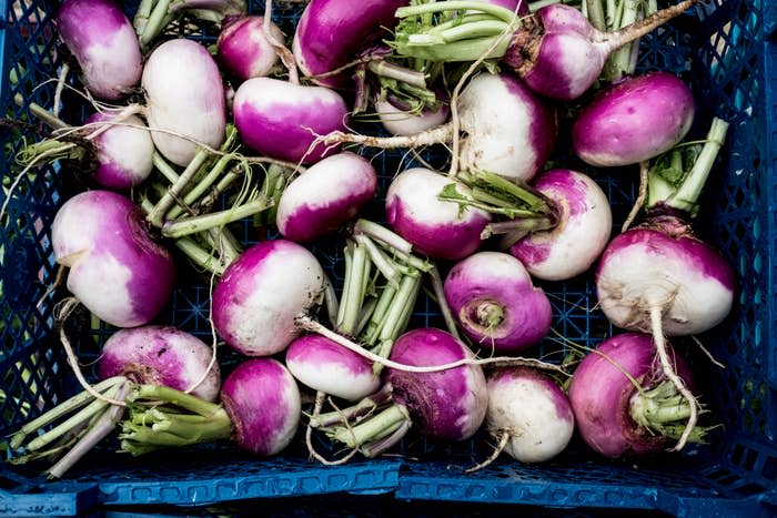 A crate filled with fresh turnips at an outdoor market