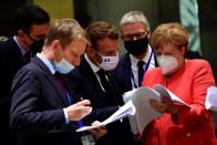 German Chancellor Angela Merkel, right, speaks with French President Emmanuel Macron, center, during a round table meeting at an EU summit in Brussels, Monday, July 20, 2020. Weary European Union leaders are expressing cautious optimism that a deal is in sight on their fourth day of wrangling over an unprecedented budget and coronavirus recovery fund. (John Thys, Pool Photo via AP)