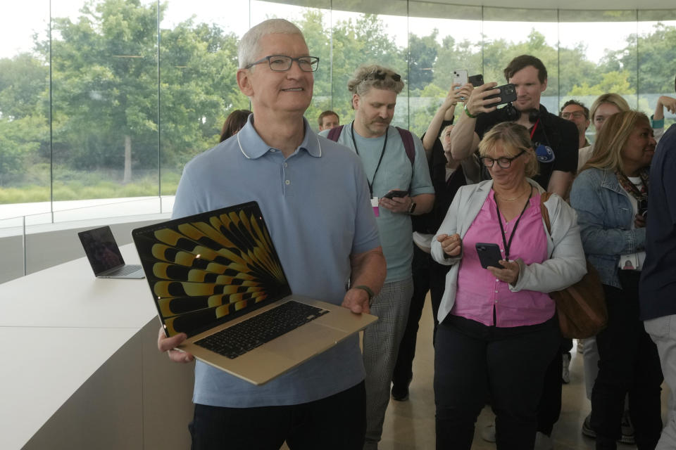 Apple CEO Tim Cook holds one of the company's new MacBooks at Apple's campus Monday, June 5, 2023 in Cupertino, Calif. (AP Photo/Jeff Chiu)