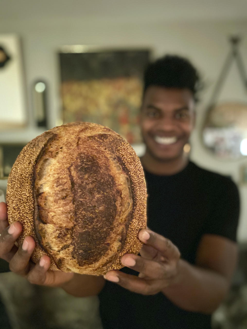 Broadway performer Max Kumangai holds a loaf of sourdough bread at his apartment in New York. The triple threat from the musical “Jagged Little Pill” has leaned into a fourth skill as the pandemic marches on: baking and selling his own sourdough. (Michael Lowney/Humpday Dough via AP)