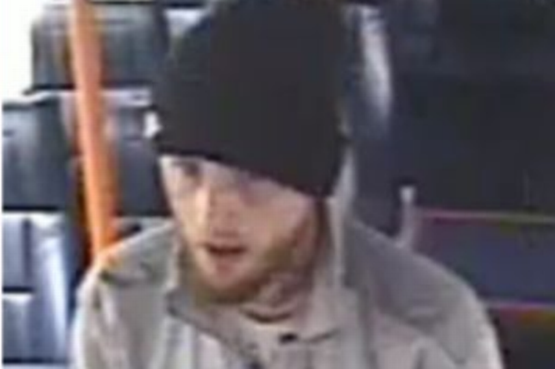 A man in a black beanie hat and grey jacket is pictured on a bus