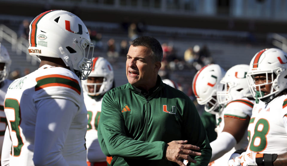 FILE - Miami football head coach Mario Cristobal talks to a player before an NCAA college football game against Boston College, Friday, Nov. 24, 2023 in Boston. The Hurricanes made a good case as the winners of the spring transfer window landing all-Pac-12 RB Damien Martinez (Oregon State), WR Sam Brown (Houston), DT Simeon Barrow (Michigan State), LB Jaylin Alderman (Louisville) and CB Dyoni Hill (Marshall). (AP Photo/Mark Stockwell, File)