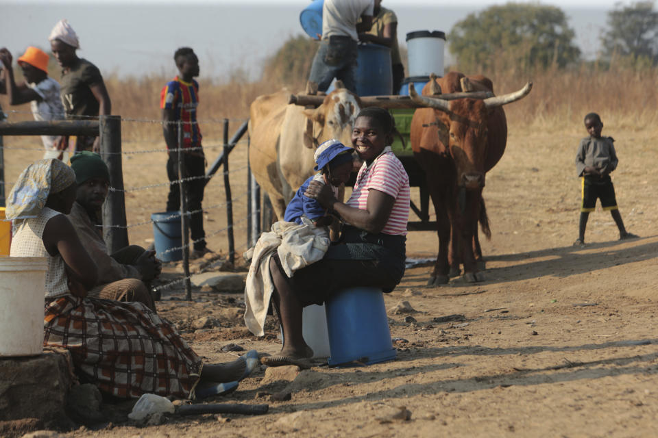 A woman smiles while playing with her baby at a water point on the outskirts of the capital Harare, Sunday, Nov, 14, 2021. When the coronavirus first emerged last year, health officials feared the pandemic would sweep across Africa, killing millions and destroying the continent’s fragile health systems. Although it’s still unclear what COVID-19’s ultimate toll will be, that catastrophic scenario has yet to materialize in Zimbabwe or much of Africa. (AP Photo/Tsvangirayi Mukwazhi)