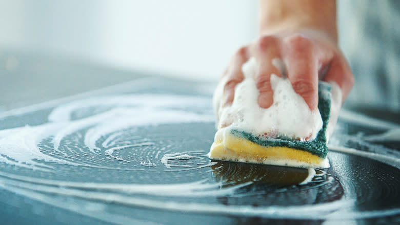 cleaning kitchen surface with sponge