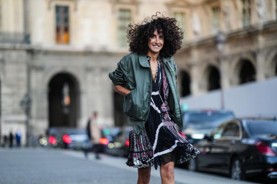 Street Style : Day Nine - Paris Fashion Week - Womenswear Spring Summer 2022PARIS, FRANCE - OCTOBER 05: A guest wears a silver chain pendant necklace, a black with embroidered burgundy / white / blue embroidered pattern buttoned V-neck pleated / accordion short dress, a khaki oversized rain coat, a silver watch, outside Louis Vuitton, during Paris Fashion Week - Womenswear Spring Summer 2022, on October 05, 2021 in Paris, France. (Photo by Edward Berthelot/Getty Images)