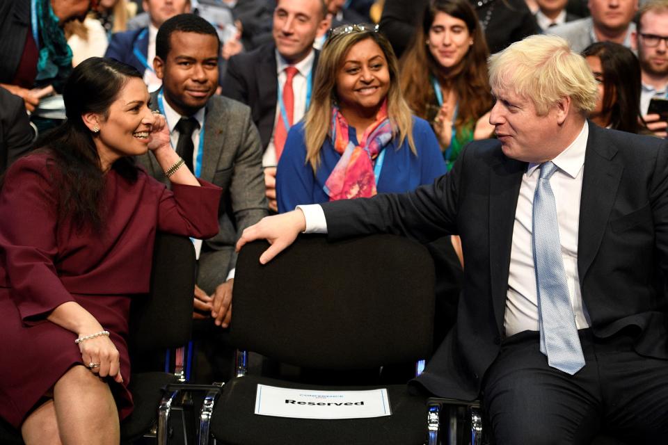 Britain's Home Secretary Priti Patel (L) and Britain's Prime Minister Boris Johnson (R) attend the second day of the annual Conservative Party Conference being held at the Manchester Central convention centre in Manchester, northwest England, on October 4, 2021. (Photo by Oli SCARFF / AFP) (Photo by OLI SCARFF/AFP via Getty Images)