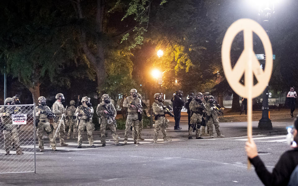 Federal agents disperse Black Lives Matter protesters near the Mark O. Hatfield United States Courthouse on Monday, July 20, 2020, in Portland, Ore. Officers used teargas and projectiles to move the crowd after some protesters tore down a fence fronting the courthouse. (AP Photo/Noah Berger)