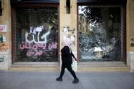 A woman walks past a closed bank office in Beirut