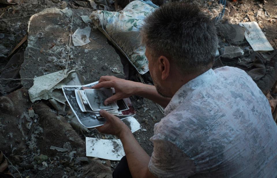 A local resident collects photos of his family left under the rubble after Russian shelling in Mykolaiv, Ukraine (George Ivanchenko/AP) (AP)