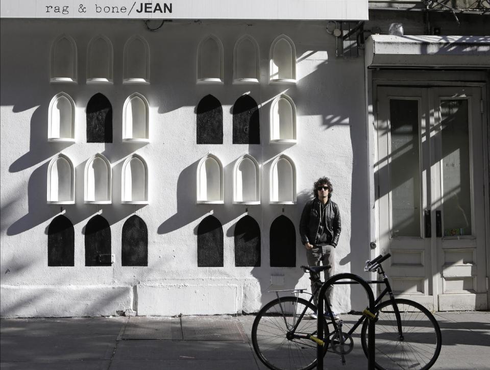 This Oct. 24, 2013 photo shows The Strokes' drummer Fabrizio Moretti in front of his installation on the exterior wall of the SoHo Rag & Bone store in New York. The installation is part of the clothing brand's ongoing urban art project, in which they get artists to revamp the store's façade. (AP Photo/Kathy Willens)