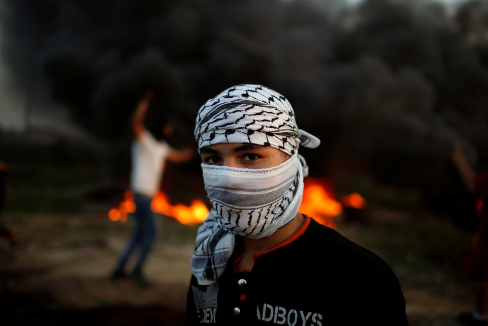 <p>A Palestinian protester, who identified himself as Ahmed, poses for a photograph in front of burning tires at the scene of clashes with Israeli troops near the border with Israel, east of Gaza City, Jan. 12, 2018. “We are the fuel of the Intifada, but we are hungry and at home we have no electricity and our fathers have no jobs. This can’t bring about anything except an explosion,” he said. (Photo: Mohammed Salem/Reuters) </p>