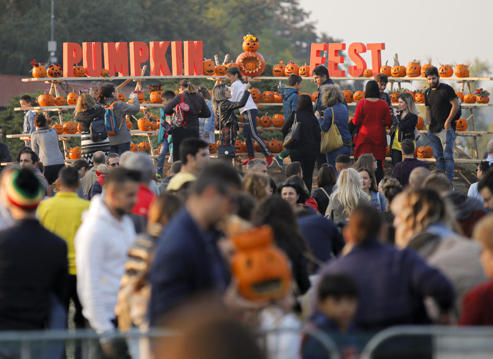 In this Saturday, Oct. 26, 2019 photo people take pictures of Halloween pumpkins at The Halloween Pumpkin Fest in Bucharest, Romania. The Halloween Pumpkin Fest, "the biggest pumpkin carving event in Europe", according to organizers, took place over the weekend in a popular park in the Romanian capital with thousands trying their hand at carving more than 30 thousand pumpkins ahead of Halloween.(AP Photo/Vadim Ghirda)