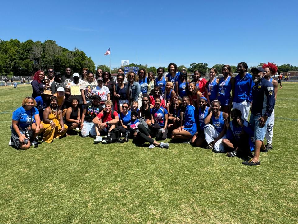 Pine Forest track and field head coach Paul Bryan, who also coached at Woodham, takes a group photo with some his current and former track and field athletes during a surprise ceremony at the Escambia County Championships on Saturday, April 13, 2024.