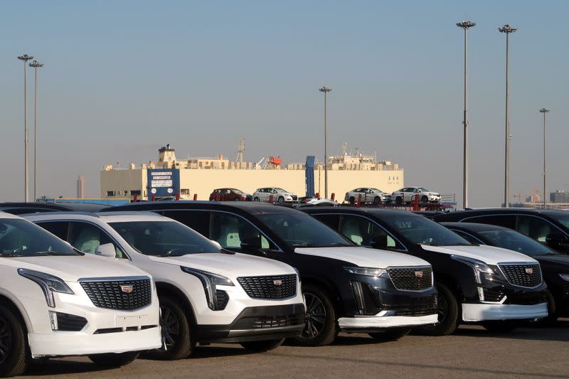 FILE PHOTO: Cadillac sport-utility vehicles are seen in front of a cargo vessel at a ro-ro terminal in Tianjin port