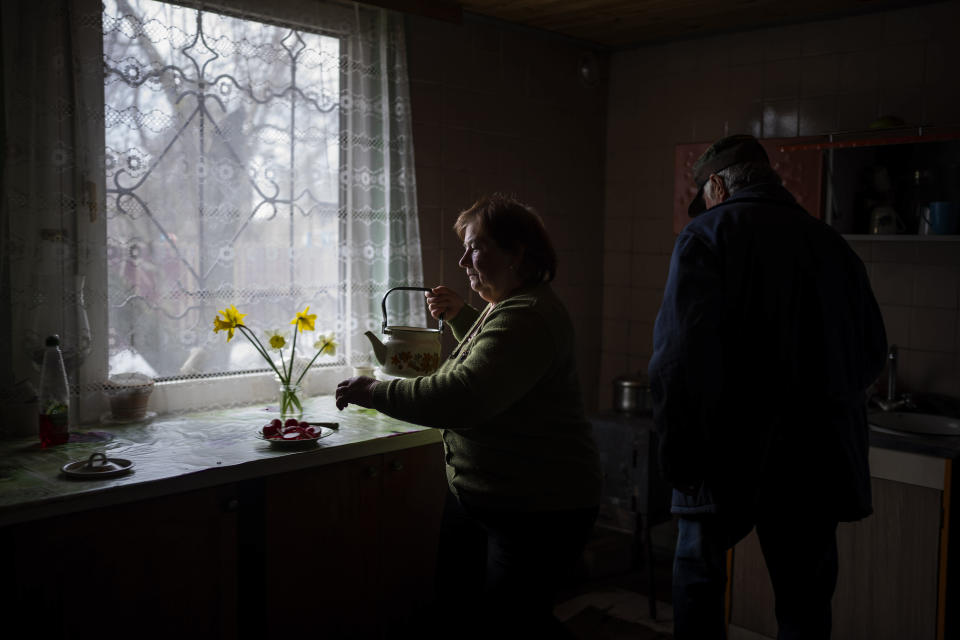 Valya Voronets, 66, prepares tea with her husband Myhailo Scherbakov, 65, in their house near the cemetery in Walnut Street in Mykulychi, Ukraine on Sunday, April 17, 2022. In the Scherbakovs' house they are still without electricity, water and gas after more than 42 days since the Russian invasion began. A Russian soldier once came running and pointed his gun at Myhailo after spotting him climbing onto the roof to get a cellphone signal. "Are you going to kill an old man?" he replied. Not all the Russians were like that. Voronets said she cried together with another soldier, barely 21. "You're too young," she told him. Another soldier told her they didn't want to fight. Still, she feared them all. But she offered them milk from her only cow. "I felt sorry for them in these conditions," she said. "And if you're nice to them, maybe they won't kill you." (AP Photo/Emilio Morenatti)