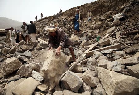 A man searches for survivors on the rubble of houses destroyed by an air strike in the Okash village near Sanaa April 4, 2015. REUTERS/Mohamed al-Sayaghi