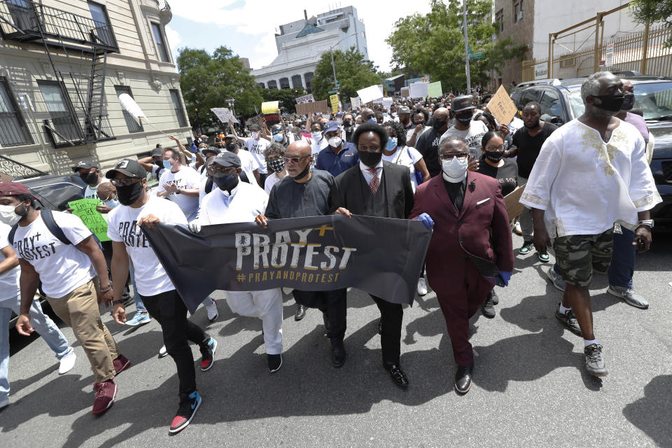 Local religious leaders hold a banner as they march through the streets of the Bedford-Stuyvesant neighborhood of the Brooklyn borough of New York, Sunday, June 7, 2020, in New York. The protest came in the wake of the May 29 death of George Floyd, who died in the custody of four Minneapolis police officers. (AP Photo/Kathy Willens)