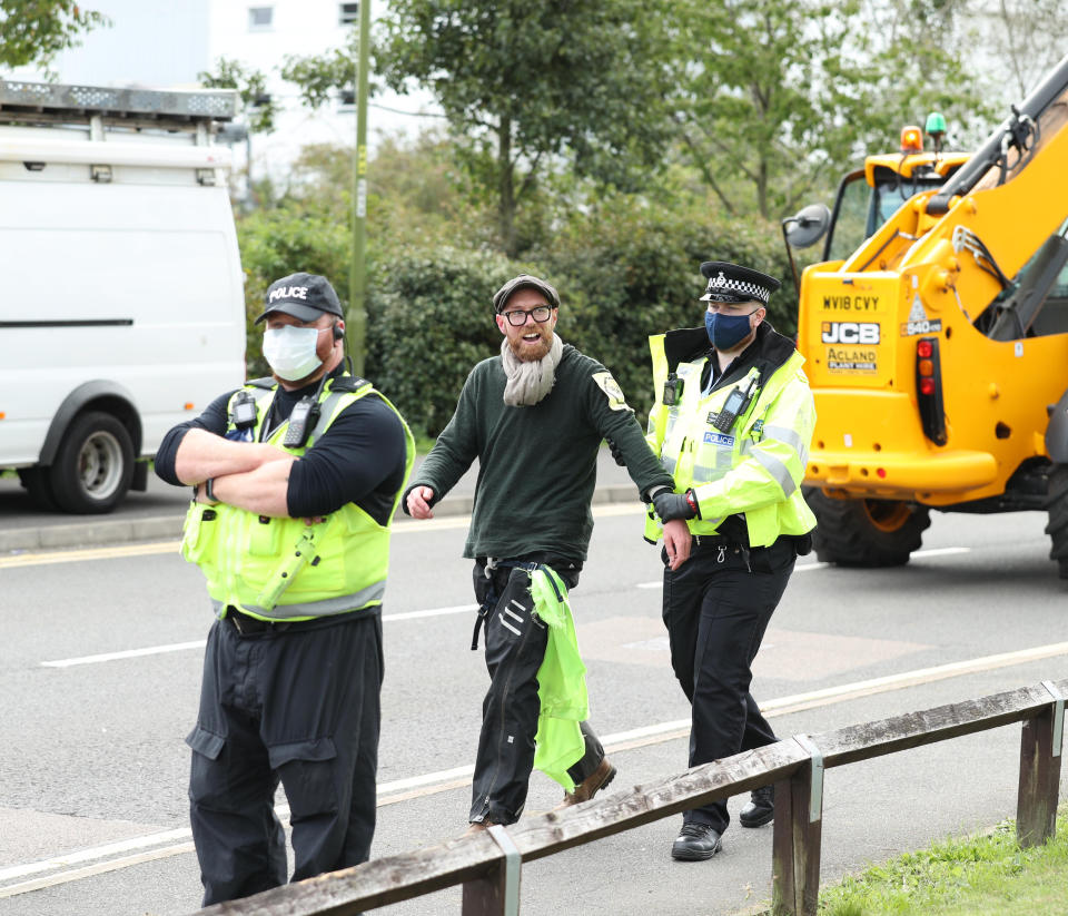 One of the protesters from the bamboo lock-ons is lead away by a police officer outside the Newsprinters printing works at Broxbourne, Hertfordshire. (Photo by Yui Mok/PA Images via Getty Images)