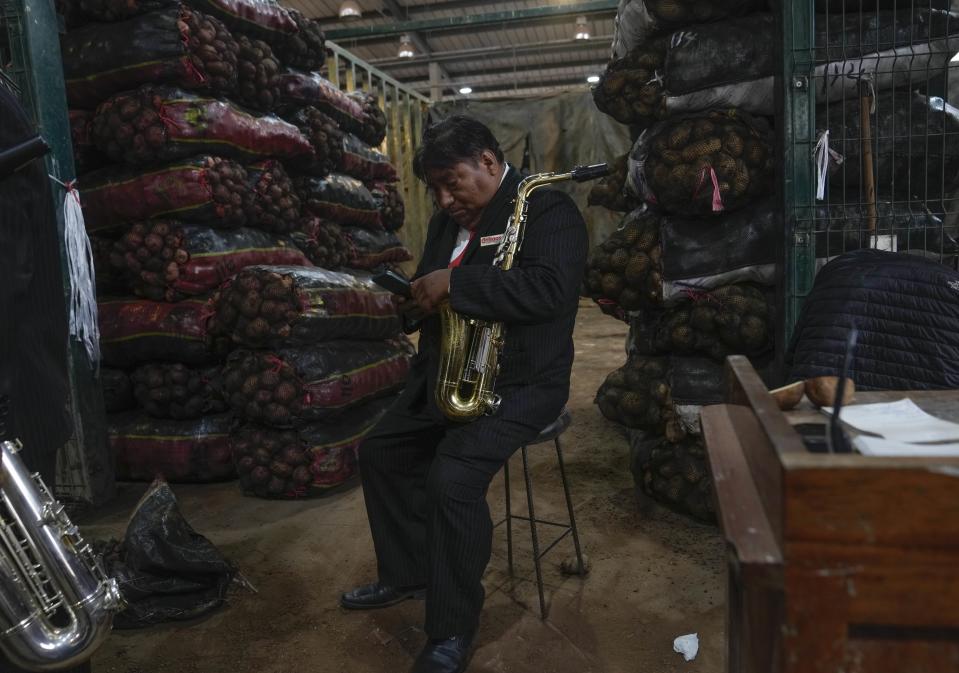 Rubén Cruz, de la banda musical "Los Amigos", descansa junto a las papas a la venta en un mercado a las afueras de Lima, después de ofrecer un show por el Día Internacional de la Papa, el jueves 30 de mayo de 2024. (AP Foto/Martín Mejía)