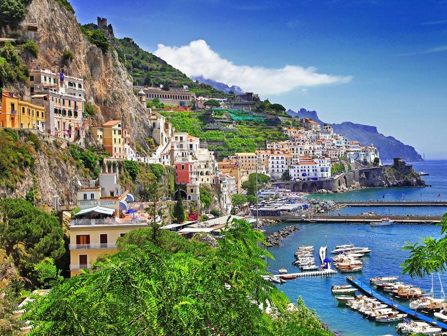 The Amalfi Coast dotted with colorful houses and foliage overlooking a harbor.