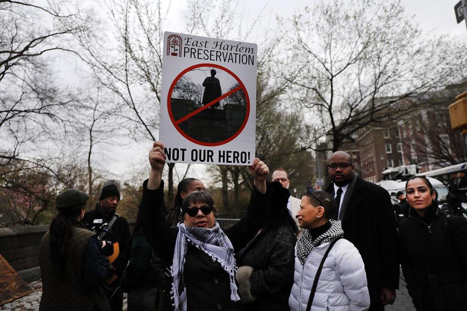 People gather to watch as a statue of J. Marion Sims is taken down.