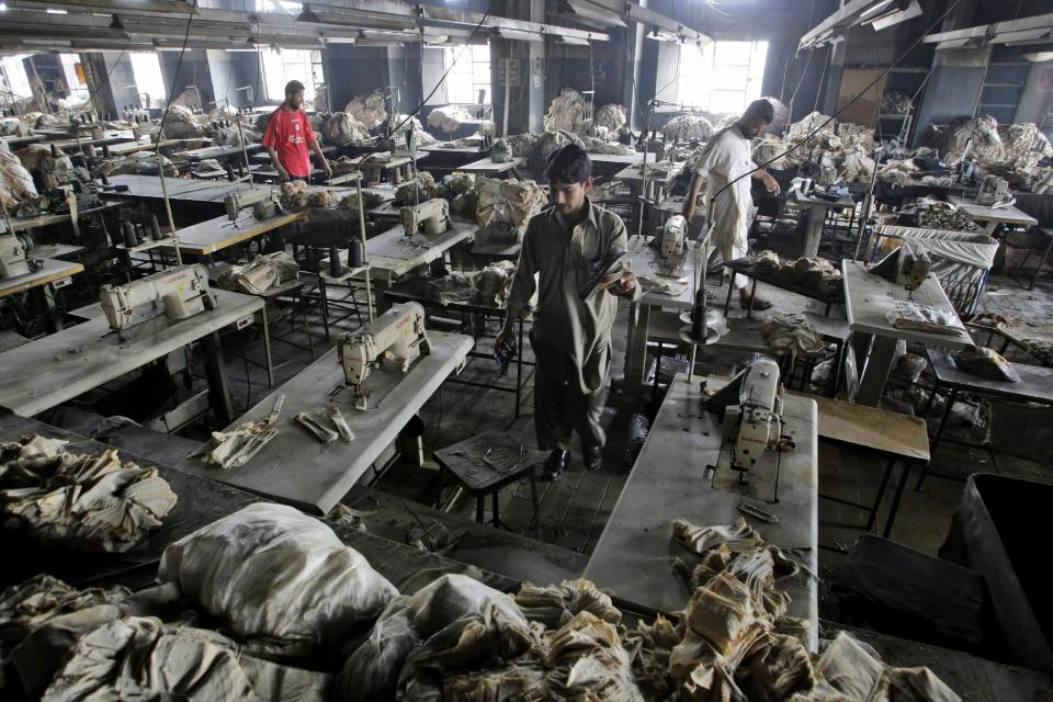 In this Thursday, Sept. 13, 2012 photo, Pakistani men check a burnt garment factory, in Karachi, Pakistan. At the only morgue in Pakistan's largest city lie the blackened remains of 32 people killed in one of the worst industrial accidents in the country's history, wrapped in white plastic body bags waiting for DNA tests to determine who they are and where they belong. (AP Photo/Fareed Khan)