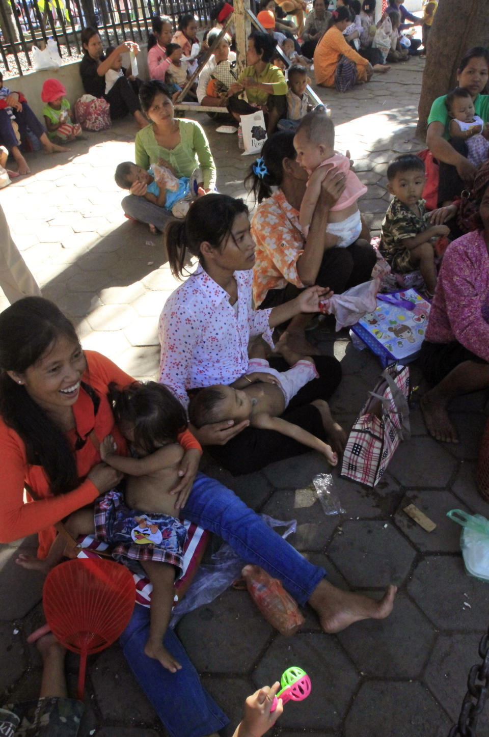 Cambodian villagers from countryside hold their children as they wait for a medical check up for their children, outside a children hospital of Kuntha Bopha, in Phnom Penh, Cambodia, Monday, July 9, 2012. A deadly form of a common childhood illness has been linked to many of the mysterious child deaths in Cambodia that caused alarm after a cause could not immediately be determined, health officials said Monday. (AP Photo/Heng Sinith)