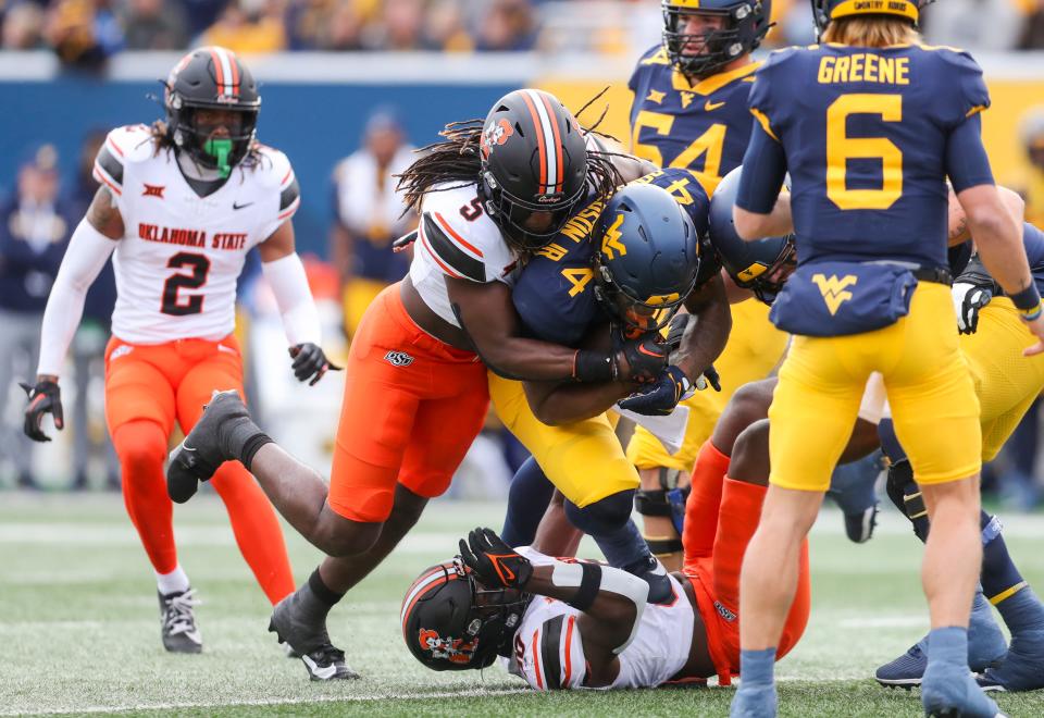 Oklahoma State safety Kendal Daniels (5) tackles West Virginia Mountaineers running back CJ Donaldson Jr. (4) during the first quarter of Saturday's game in Morgantown, W. Va.