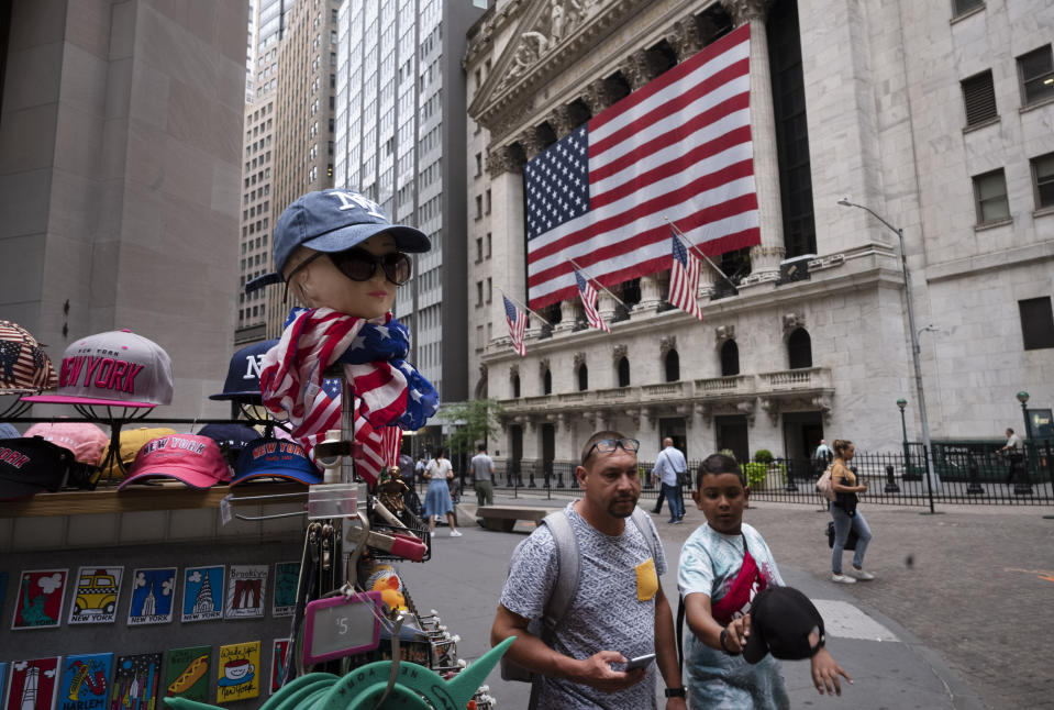 People walk by a souvenir stand in front of the New York Stock Exchange, Friday, July 5, 2019 in New York. (AP Photo/Mark Lennihan)